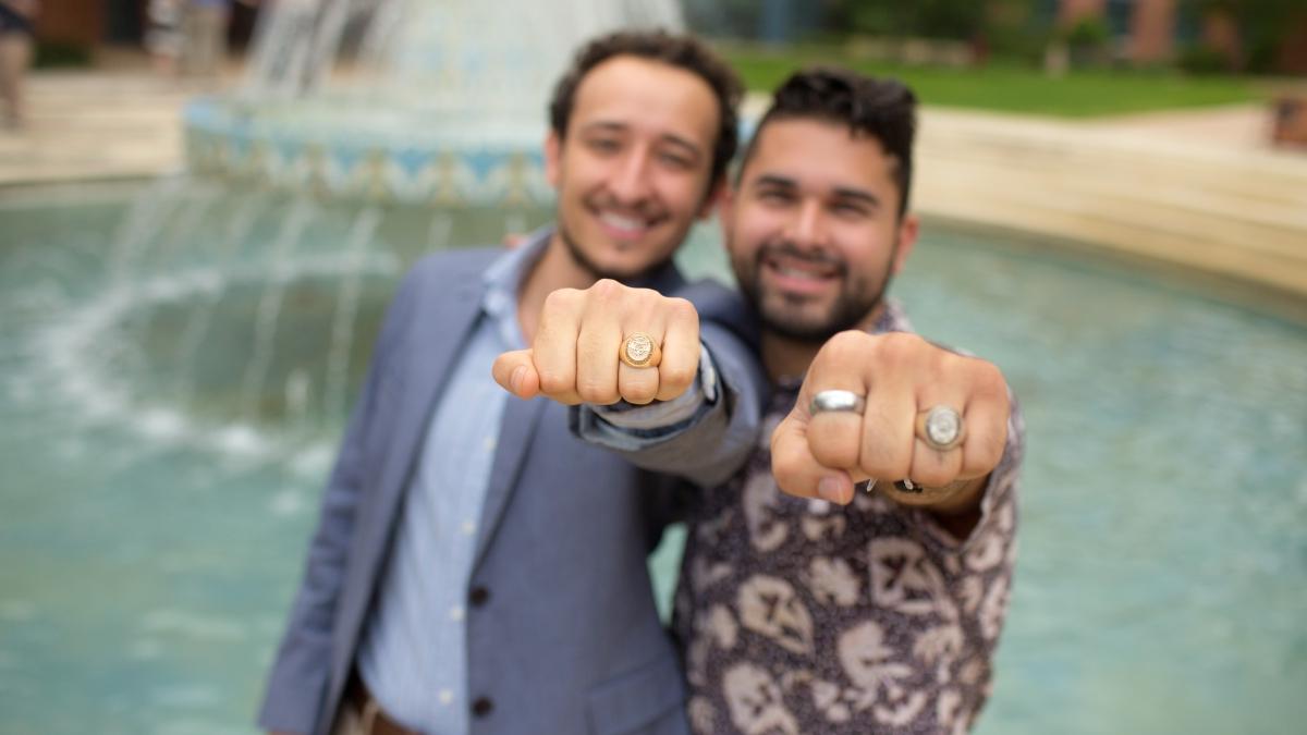 两个学生在米勒喷泉旁炫耀他们的班级戒指