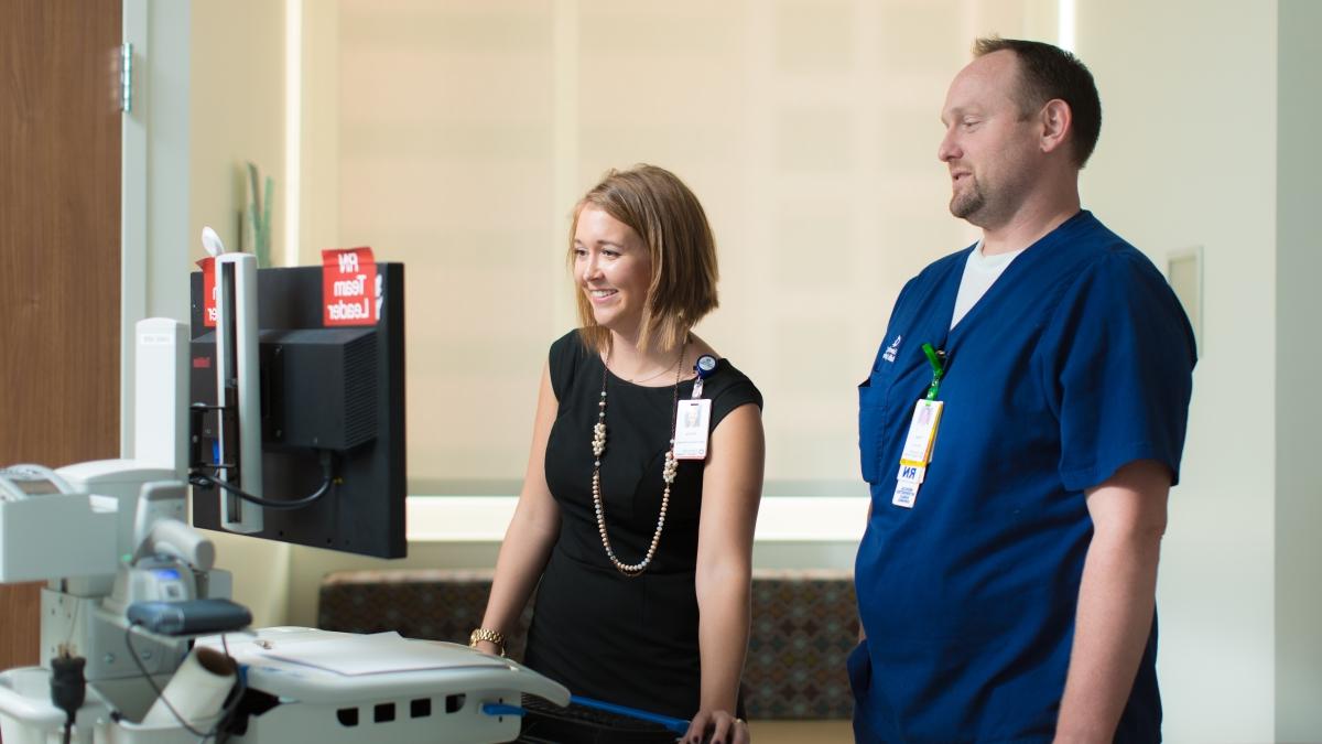 a nurse and a hospital executive look at a monitor inside a patient suite
